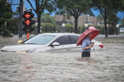 Desde la noche del sábado hasta última hora del martes, cayeron en Zhengzhou 617 litros de lluvia, una cantidad que casi iguala la media anual de precipitaciones que se recogen en esta ciudad. En la imagen, una persona pasa cerca de un coche sumergido, en una calle de Zhengzhou.
