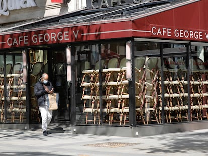 Um homem passa diante de um café fechado em Paris.