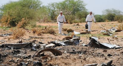 Dos forenses inspeccionan los restos del avi&oacute;n que se estrell&oacute; en Mal&iacute; en julio del a&ntilde;o pasado.