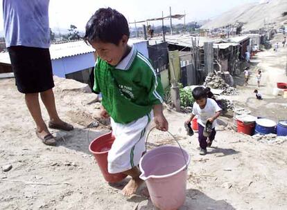 Un niño lleva agua en un poblado de chabolas de la periferia de Lima.