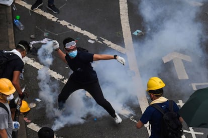 Un manifestante devuelve un bote de gas lacrimógeno en los enfrentamientos con la policía junto a la sede del Gobierno en Hong Kong. Al menos 22 personas, según los medios del territorio autónomo, han resultado heridas. El Parlamento ha aplazado, sin precisar hasta cuándo, la sesión para tramitar el proyecto de ley.