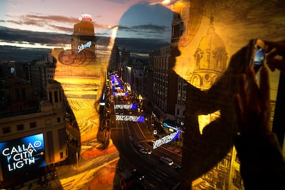 La silueta de una mujer se refleja en el cristal de un restaurante donde se puede ver la Gran Vía de Madrid (España) iluminada con las luces navideñas, el 28 de noviembre de 2016.