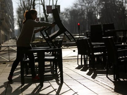 Una camarera monta una terraza en Madrid.