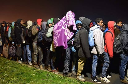 Inmigrantes hacen cola para subir esta mañana para subir a los autobuses que los trasladarán.