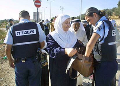 Una policía registra el bolso de una palestina en el control entre Belén y Jerusalén.