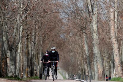 Unas personas circulan en bicicleta por la Casa de Campo de Madrid.