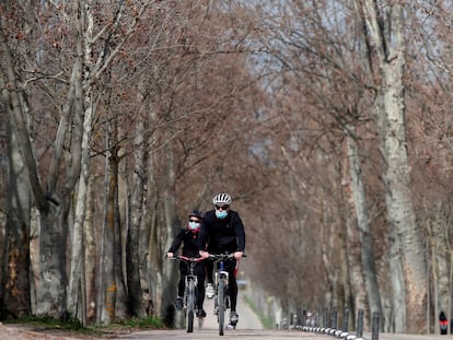 Unas personas circulan en bicicleta por la Casa de Campo de Madrid.