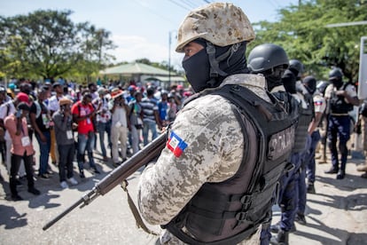 An armed police officer watches over a protest by journalist in Port-au-Prince.