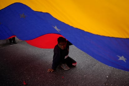 Un niño juega bajo una bandera de Venezuela durante una marcha en Caracas, en febrero de 2022.