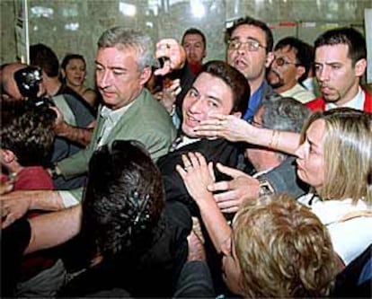 Joaquín José Martínez (con corbata), rodeado por una multitud, a su llegada al aeropuerto de Barajas.