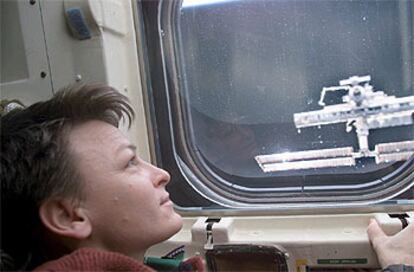La astronauta Peggy Whitson, de la Expedición 5, mira la ISS desde la ventana del transbordador.
