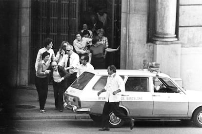 Para que no quede duda de sus intenciones, el jefe de los secuestradores dispara en una pierna de manera intencionada a uno los rehenes, un joven trabajador de la entidad. Se establece una línea telefónica con la sede del vecino Banco de Bilbao, donde se ha instalado el centro de operaciones policial. Los asaltantes se identifican como guardias civiles. Una convicción que durará todo el asalto y que es reafirmada por los testimonios de los rehenes que son intercambiados por comida y tabaco. Las autoridades creen firmemente que se encuentran ante un grupo organizado en tres comandos de ocho individuos, que cuentan con explosivos y armamento idéntico al que utiliza la Guardia Civil, disciplina, jerarquía y experiencia militar. En la imagen, varios rehenes salen del banco, el sábado 23.