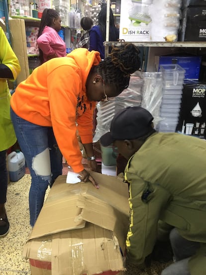 Ashley Karanja, junto con un vendedor, empaqueta artículos para su cliente en una tienda de Nairobi, Kenia.