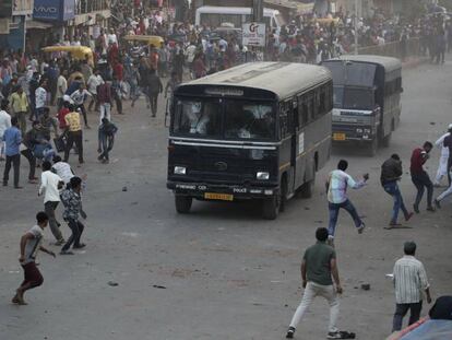 Manifestantes lanzan piedras contra vehículos policiales, este jueves en Ahmadabad (India).