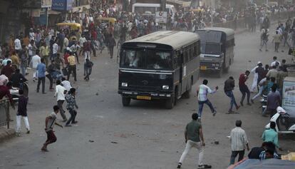 Manifestantes lanzan piedras contra vehículos policiales, este jueves en Ahmadabad (India).