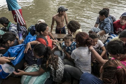Mujeres y niños suben a una balsa para cruzar el río Suchiate.