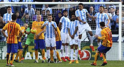 El delantero argentino del FC Barcelona Leo Messi (d) lanza una falta frente al Málaga.