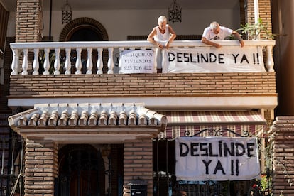 Una familia despliega una pancarta en favor de la regularización de más de 500 viviendas en la barriada de El Palo, en Málaga.