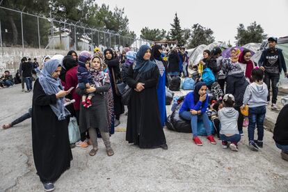 El Gobierno está acelerando los traslados y ha anunciado que hasta finales de año moverá a unas 20.000 personas. En la imagen, un grupo de personas espera en la puerta del campo la llegada de autobuses que les llevarán al puerto de Mitilene para ser trasladados a la Grecia continental.