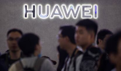 Varias personas frente a un logo de Huawei en Shanghái. 