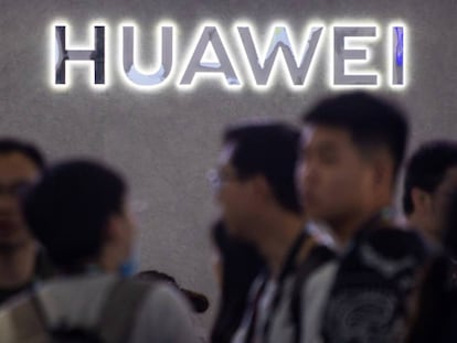 Varias personas frente a un logo de Huawei en Shanghái. 