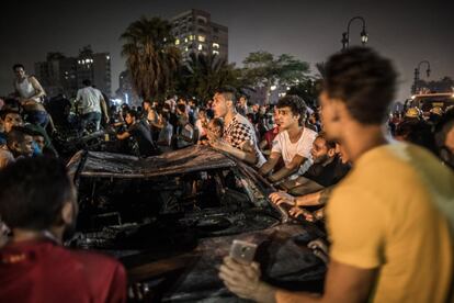 Una multitud se congrega alrededor del automóvil quemado frente al Instituto Nacional del Cáncer después de una explosión.