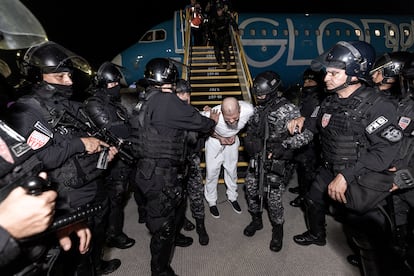 Fotografía cedida por la Presidencia de El Salvador donde se observa a Policías de la Unidad de Mantenimiento del Orden (UMO) trasladando a supuestos miembros de la banda criminal conocida como Tren de Aragua este domingo, en el aeropuerto internacional Óscar Arnulfo Romero, en San Luis Talpa.