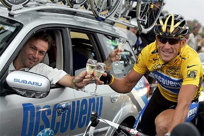 Lance Armstrong brinda con champagne encima de su bici con el director de del Discovery Channel, Johan Bruyneel.