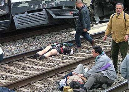 Algunas víctimas recorren las vías de la estación de Atocha momentos después el atentado, mientras otras yacen en el suelo.