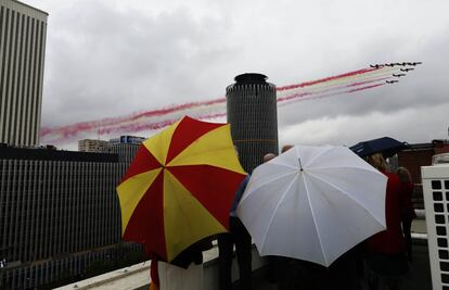 Varias personas contemplan desde una azotea el ejercicio de la Patrulla Águila durante el desfile de las Fuerzas Armadas en Madrid.