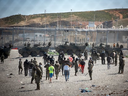 Un grupo de militares acompaña a varios inmigrantes llegados por mar a la playa ceutí del Tarajal, el pasado martes.