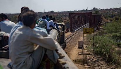 Un tren con el techo repleto de viajeros cruza el puente sobre el río Kuno, entre Gwalior a Sheopur, India.