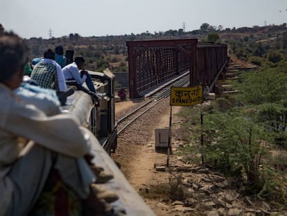 Un tren con el techo repleto de viajeros cruza el puente sobre el río Kuno, entre Gwalior a Sheopur, India.