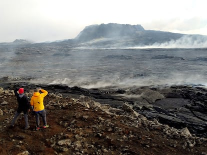 Dos personas observan el cráter apagado del volcán islandés Fagradalsfjall.