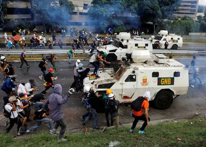 Varios manifestantes se enfrentan a un coche blindado de la policía durante una protesta en Caracas, el 1 de mayo de 2017.