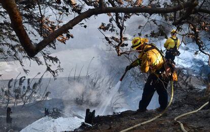 Dos bomberos trabajan para extinguir el fuego en la carretera de Latigo Canyon, en Malibú (California), el pasado sábado.