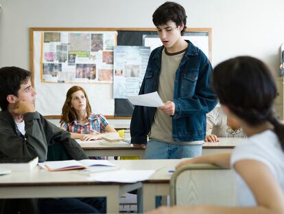 Un alumno lee un trabajo al resto del aula.