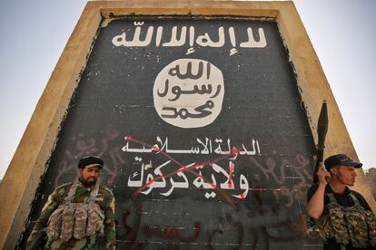 Soldados del ejército Hashed al-Shaabi (Unidades de Movilización Popular), apoyo de las fuerzas iraquíes, permanecen junto a un muro que representa al Estado Islámico, con su lema tachado, en Hawija (Iraq).