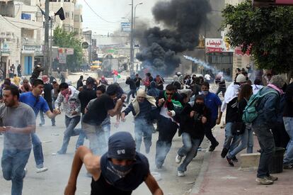 Los manifestantes palestinos huyen ante los soldados israelíes, que lanzan de gases lacrimógenos, en el puesto de control de Qalandia, puesto de control entre Jerusalén y la ciudad cisjordana de Ramala.