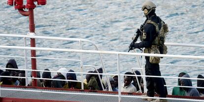 Un policía armado vigila a un grupo de inmigrantes a bordo del barco petrolero El Hiblu 1, en el Gran Puerto de La Valeta (Malta).