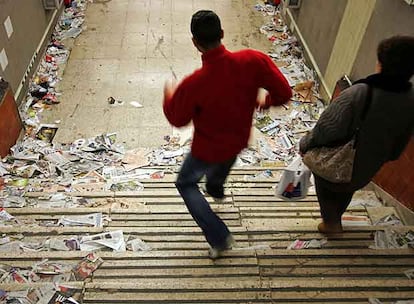 Dos viajeros acceden a una estación del metro de Madrid repleta de basura.