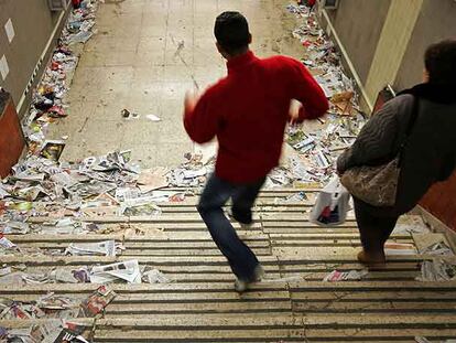 Dos viajeros acceden a una estación del metro de Madrid repleta de basura.