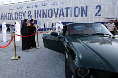 People take pictures of a displayed electric car on the sidelines of the United Nations Climate Change Conference (COP28) in Dubai, United Arab Emirates, December 10, 2023