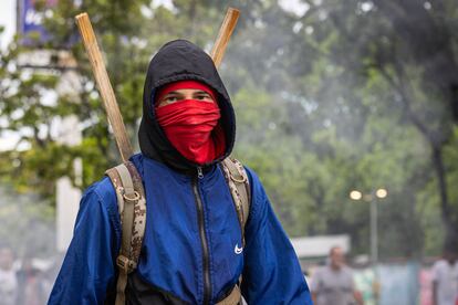 Un joven con el rostro cubierto protesta en Caracas, este lunes.