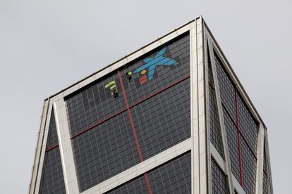 Dos operarios trabajan en la sustitución del logo de Bankia por el de CaixaBank en las torres Kio, el 27 de marzo del año pasado en Madrid.