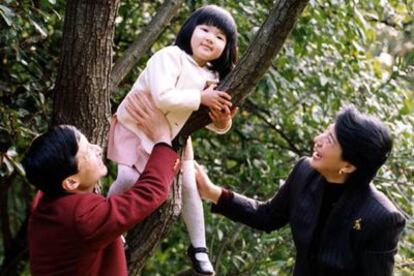 La pequeña Aiko, subida a un árbol, en presencia de sus padres.