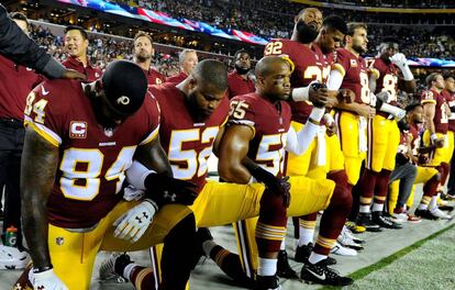 Jugadores del Washington Redskins se arrodillan durante el himno antes de un partido contra los Oakland Raiders.