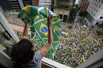 Mulher agita bandeira para manifestantes.