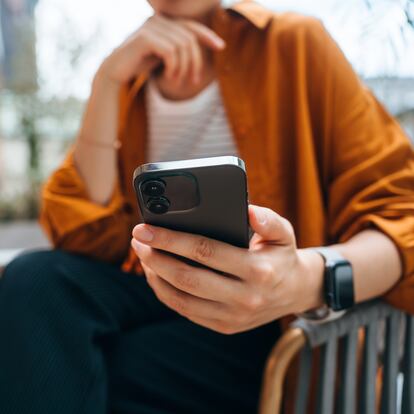 Close up shot of a young Asian woman using smartphone while sitting in an outdoor cafe and drinking coffee. Lifestyle and technology