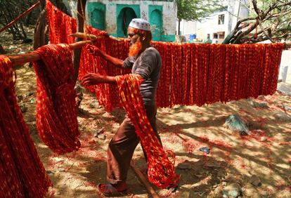 Un trabajador cuelga "Kalavas", hilos sagrados, a secar después de teñirlos con colores en Ajmer, India.